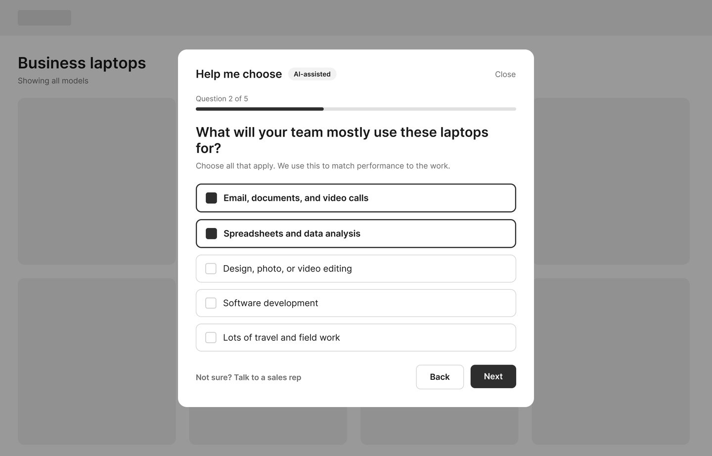 Wireframe: a question step asking what the team will use the laptops for, with checkbox answers, a question 2 of 5 progress bar, and a link to talk to a sales rep